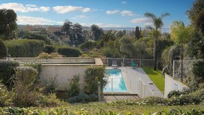 A swimming pool surrounded by lush greenery and a clear sky. - FRGK Diane Elegance and Comfort in Antibes (Antibes)