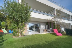A modern two-story building with a balcony, a patio with outdoor furniture, and a well-maintained lawn. - Frgk *Diane | Elegance and Comfort in Antibes* (Antibes)