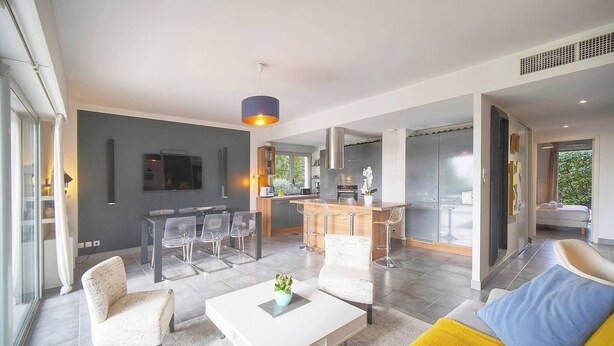 A modern living room with a dining area, kitchen, and a large window. - FRGK Diane Elegance and Comfort in Antibes (Antibes)