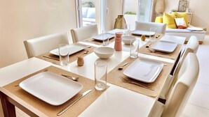 Comedor con una mesa dispuesta para cuatro personas, incluyendo platos, vasos y cubiertos.