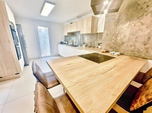Eine moderne Küche mit einer zentralen Kochinsel, Holzschränken und einem großen Fenster.