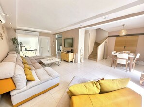 Ein modernes Wohnzimmer mit Sofa, Couchtisch und Essbereich.