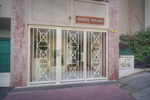 Ein Gebäudeeingang mit einem Schild, auf dem 'CANNES MELODIE' steht, und der Zahl '63' an der Wand.