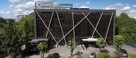 A modern building with a glass facade and a parking lot.