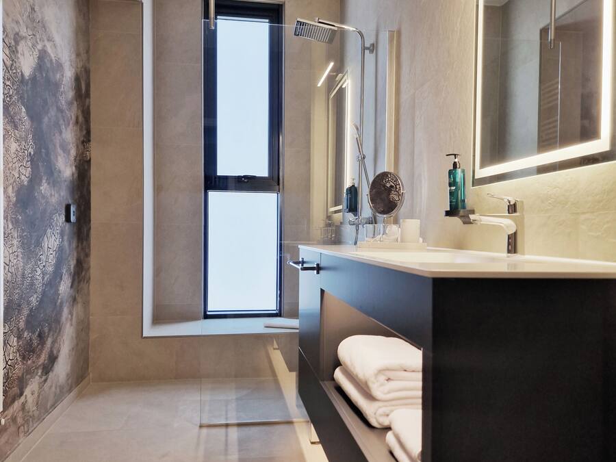 Un baño moderno con un espejo grande, una ducha y una ventana.