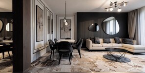 Ein modernes Wohnzimmer mit einer Couch, Sesseln, einem Couchtisch, einem Essbereich mit Stühlen und einem großen Spiegel an der Wand.