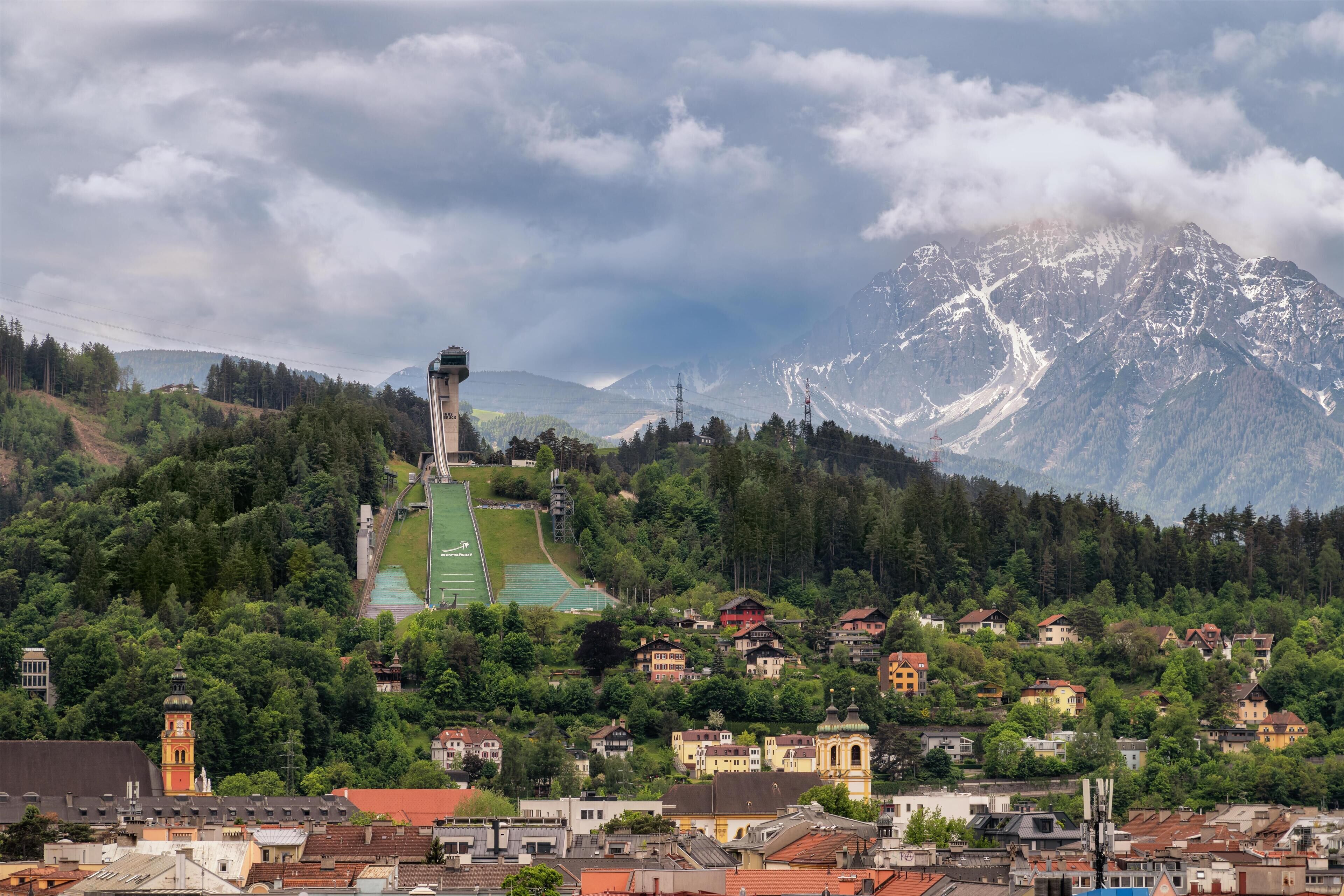 A mountainous town with a prominent church, residential buildings, and a sports field.