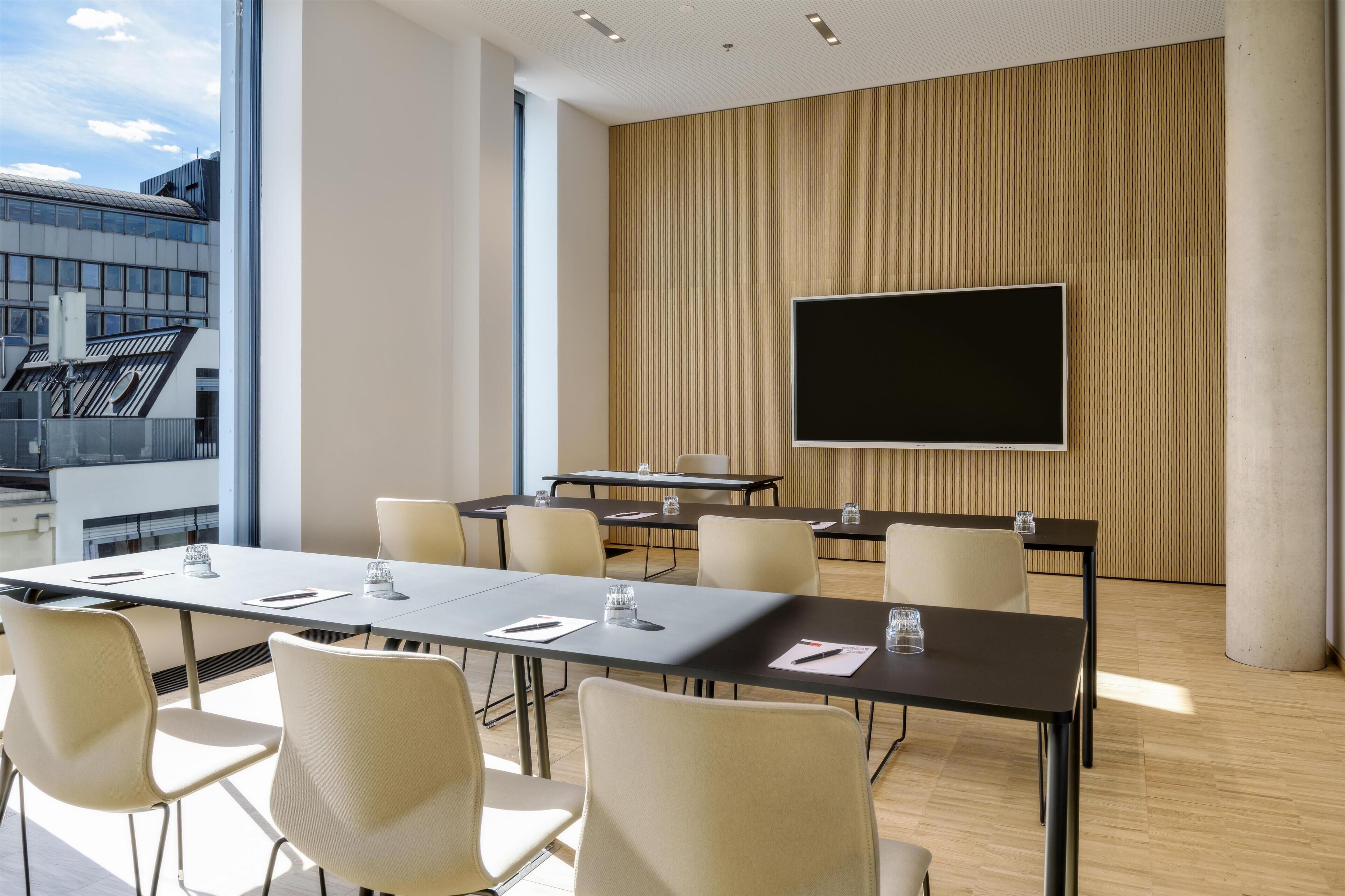 A conference room with a large screen, multiple tables, and chairs.