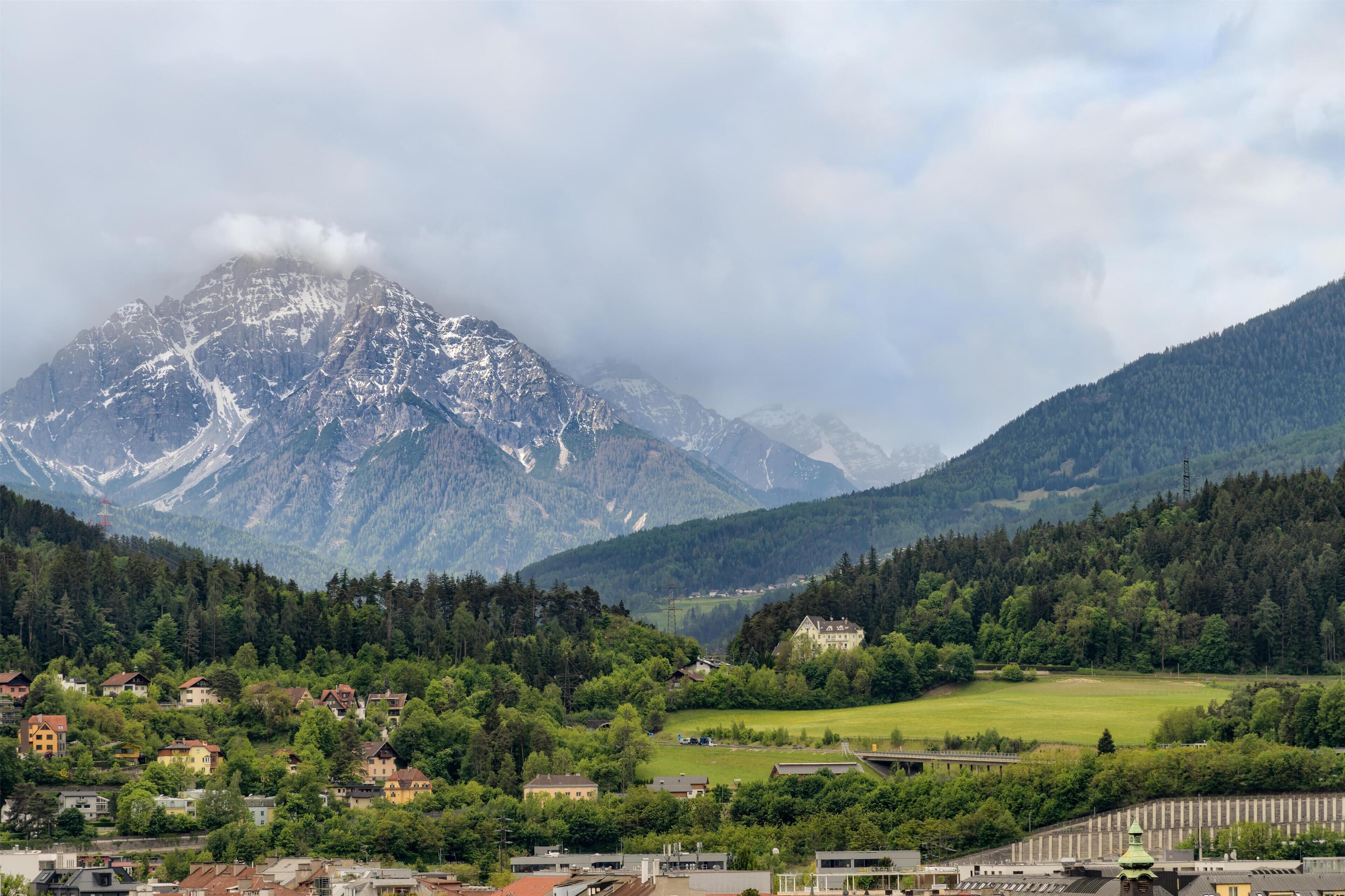 Un paysage montagneux avec un village, des maisons et un sommet de montagne bien visible.