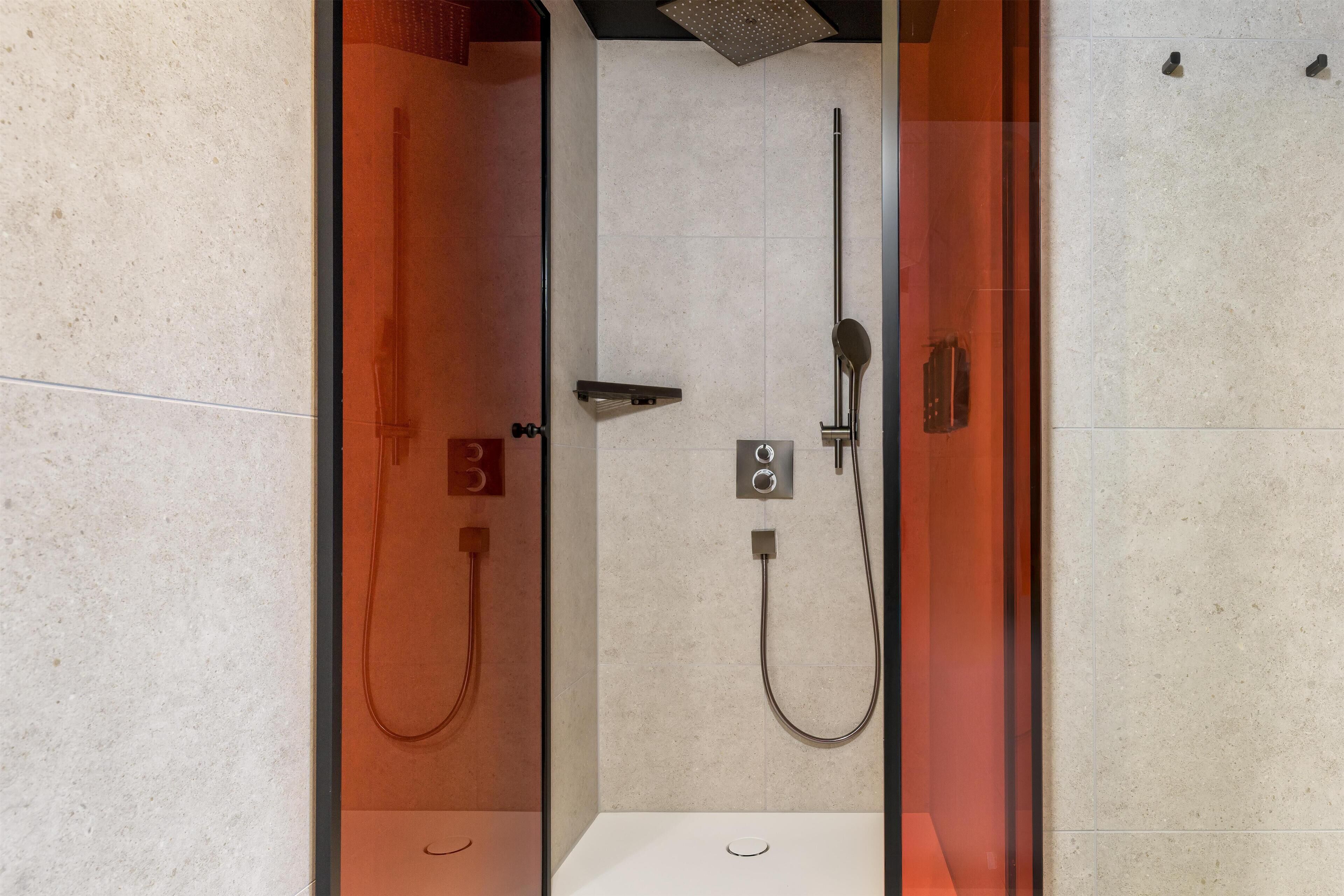 Un box de ducha moderno con un cabezal de ducha de mano, un grifo empotrado en la pared y un panel de control.
