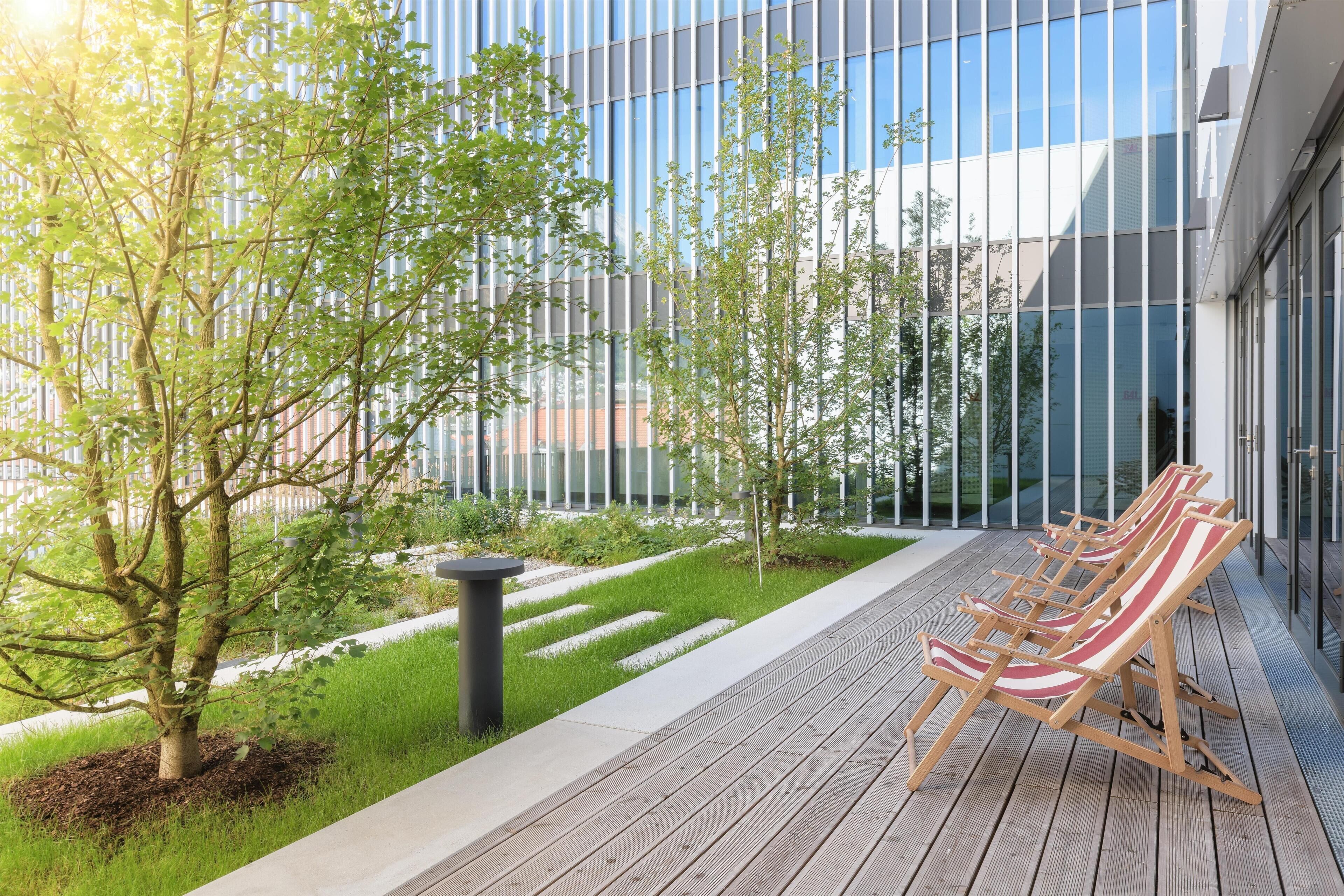 Uma área de estar moderna ao ar livre, com cadeiras de lounge e um deck de madeira.