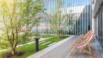 Uma área de estar moderna ao ar livre, com cadeiras de lounge e um deck de madeira.