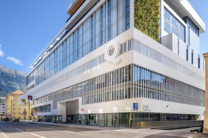 Un bâtiment moderne, caractérisé par un logo en forme de « Q » bien visible, une façade en verre et une entrée pour les piétons.