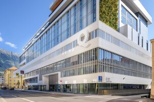 Un edificio moderno con un llamativo logotipo 'Q', fachada de vidrio y acceso para peatones.