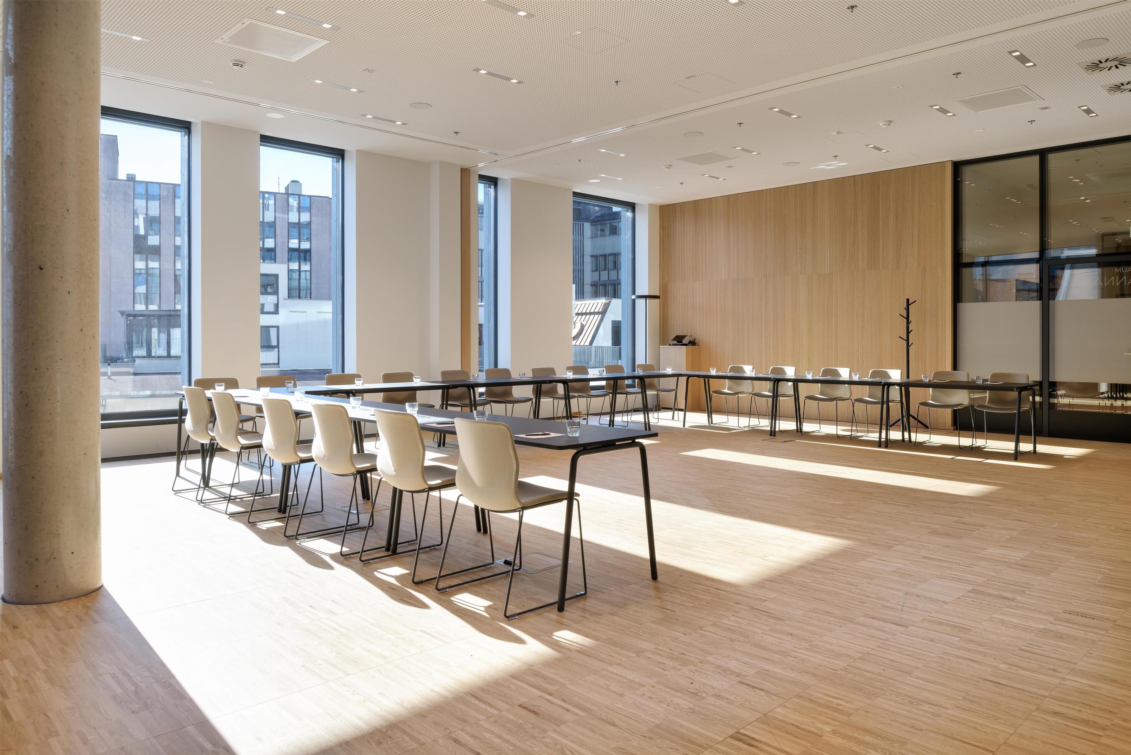 A modern conference room with large windows, a wooden panel wall, and a long table with chairs.