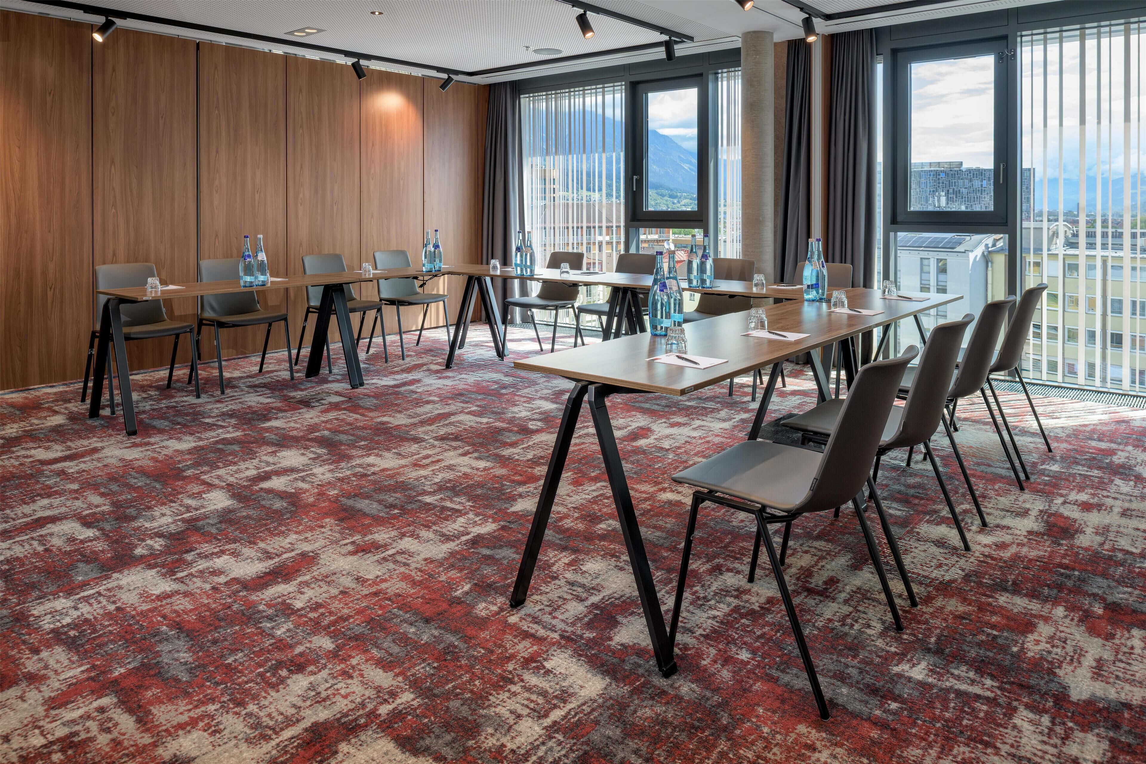 A conference room with a long table, chairs, and a carpeted floor.