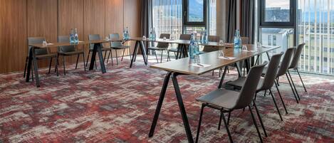 Una sala de conferencias con una mesa larga, sillas y piso alfombrado.