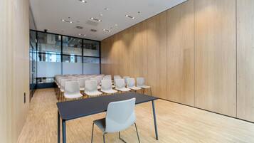 Un salón de conferencias con una larga mesa y sillas, paredes de madera e iluminación empotrada en el techo.