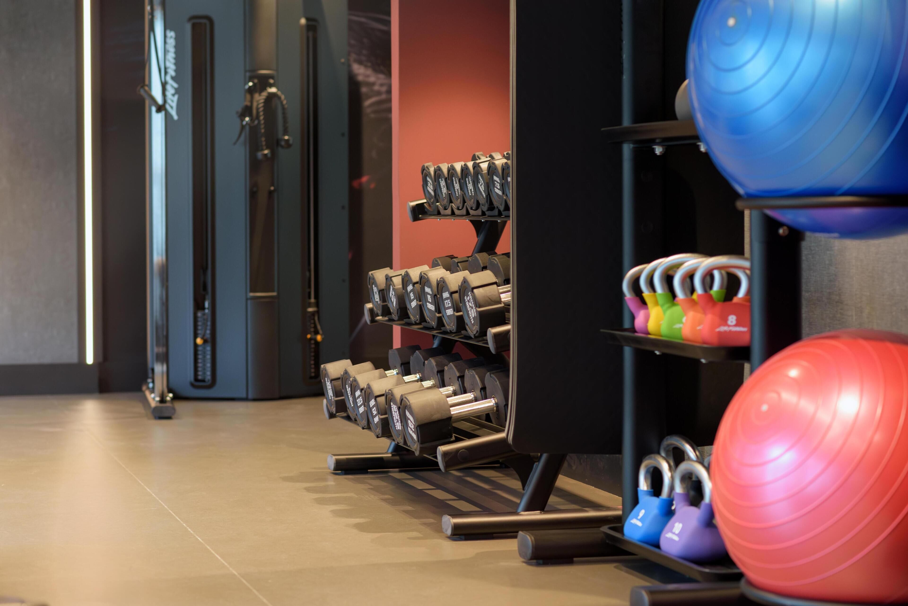 A gym with exercise equipment including dumbbells, kettlebells, and exercise balls.