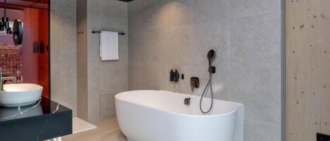 A modern bathroom with a freestanding bathtub, a large mirror, and a black countertop.