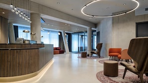 A modern lobby with a reception desk, seating area, and large windows. - Radisson Red Innsbruck (Innsbruck)
