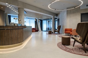A modern lobby with a reception desk, seating area, and large windows. - Radisson Red Innsbruck (Innsbruck)
