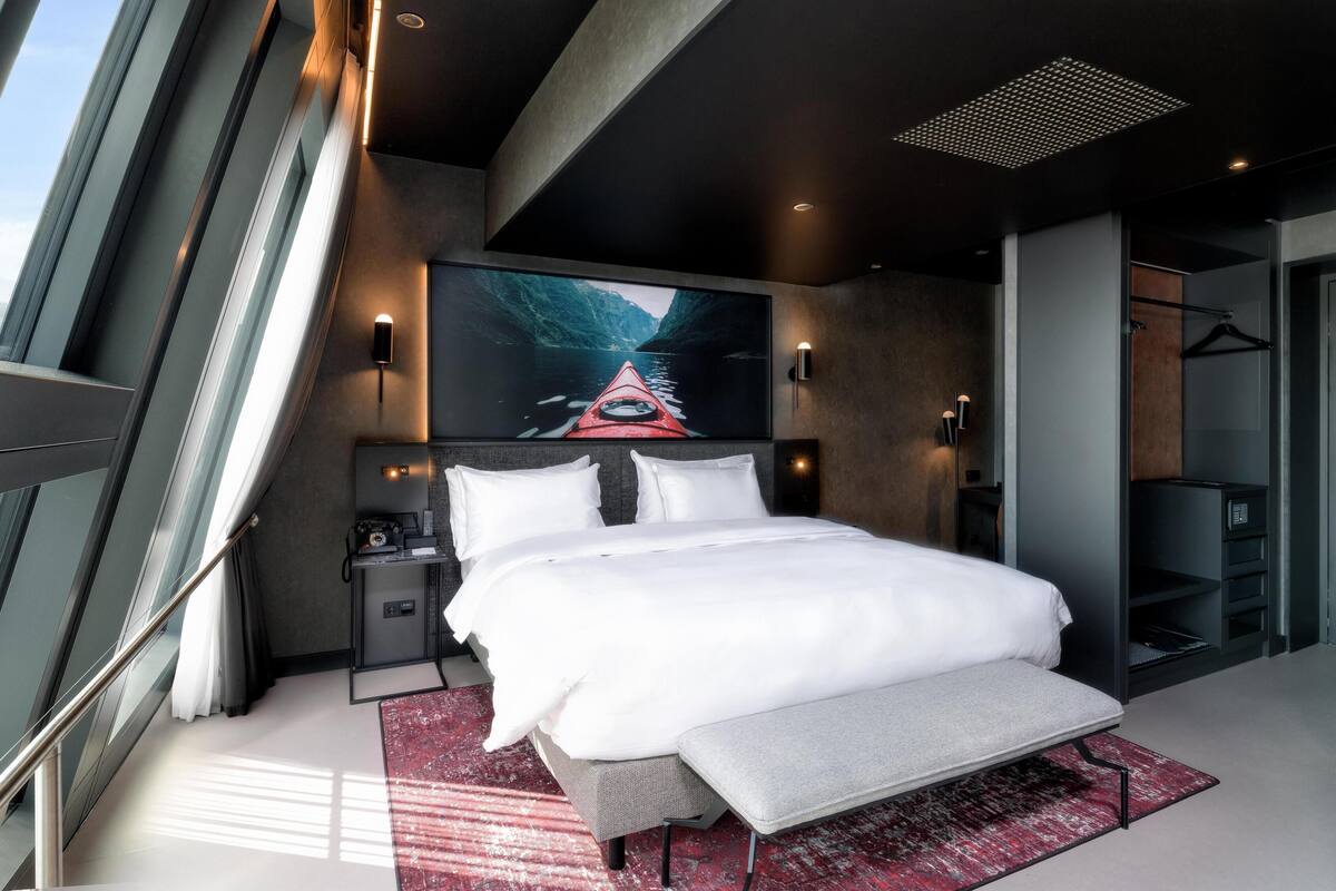 Ein modernes Hotelzimmer mit einem großen Bett, einem Schreibtisch und einem großen Fenster.