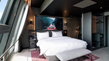 Una habitación de hotel moderna con una cama grande, un escritorio y un ventanal amplio.