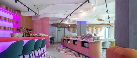 Un espacio moderno de bar con barra, taburetes y una zona de estar con suelo estampado.