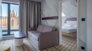 A modern hotel room with a sofa, a bed, a small table, and a patterned floor.