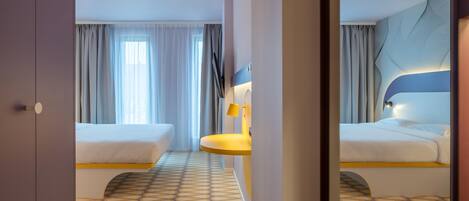 A hotel room with two beds, a bathroom with a sink, and a large mirror.