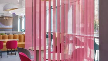 Un interior moderno con suelo de estampado geométrico, un área de estar con sillas naranja y rosa, y un separador con listones verticales.