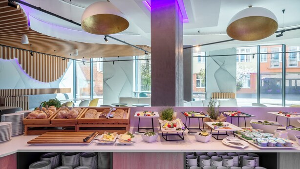 A modern breakfast buffet with various food items and a view of the city.