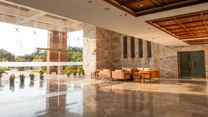 Un vestíbulo amplio con piso de mármol, mobiliario moderno y ventanas grandes.
