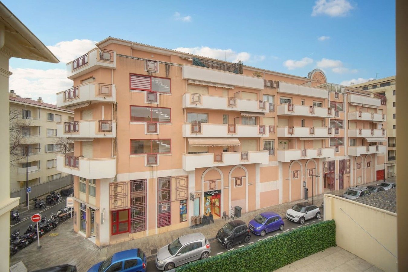 Un immeuble résidentiel à plusieurs étages, doté de balcons, d’une entrée au niveau du sol et d’un espace de stationnement.