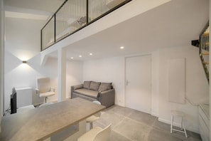 A modern interior with a dining area, a sofa, and a staircase. - Question 24. August, 2-room apartment in the center of Antibes, quiet location` (Antibes)