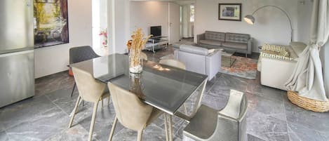 Une cuisine moderne avec un coin repas, un canapé et un téléviseur.