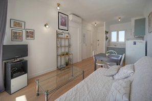 A modern living room with a glass coffee table, a television, and a bookshelf. - Frgk Fauvettes Terrace Parking, Air Conditioning, UltraFast Wi-Fi (Cannes)