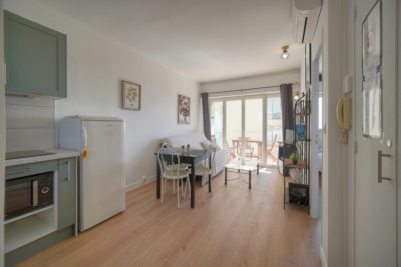 Un espacio habitable compacto con kitchenette, zona de comedor y balcón.