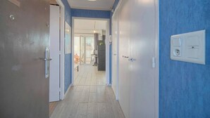 En hall med en dörr på vänster sida, en lampa ovanför och ett eluttag på höger sida.