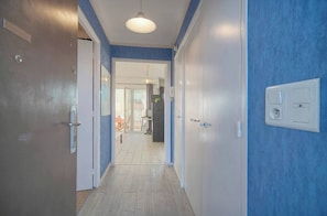 A hallway with a door on the left, a light fixture above, and a wall socket on the right. - THE WILDLIFE (Cannes)