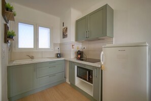 Eine Küche mit Einbauofen, Kühlschrank und Fenster.