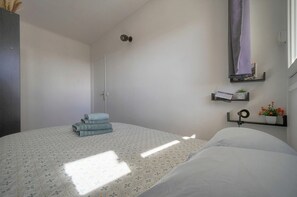 A bedroom with a bed, a door, a shelf with a calendar, and a small plant. - Frgk Fauvettes Terrace Parking, Air Conditioning, UltraFast Wi-Fi (Cannes)