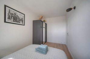 Une chambre à coucher avec un lit, une armoire, un tableau encadré au mur et une porte.