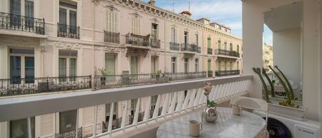 Un balcon avec une table, des chaises et un ventilateur.