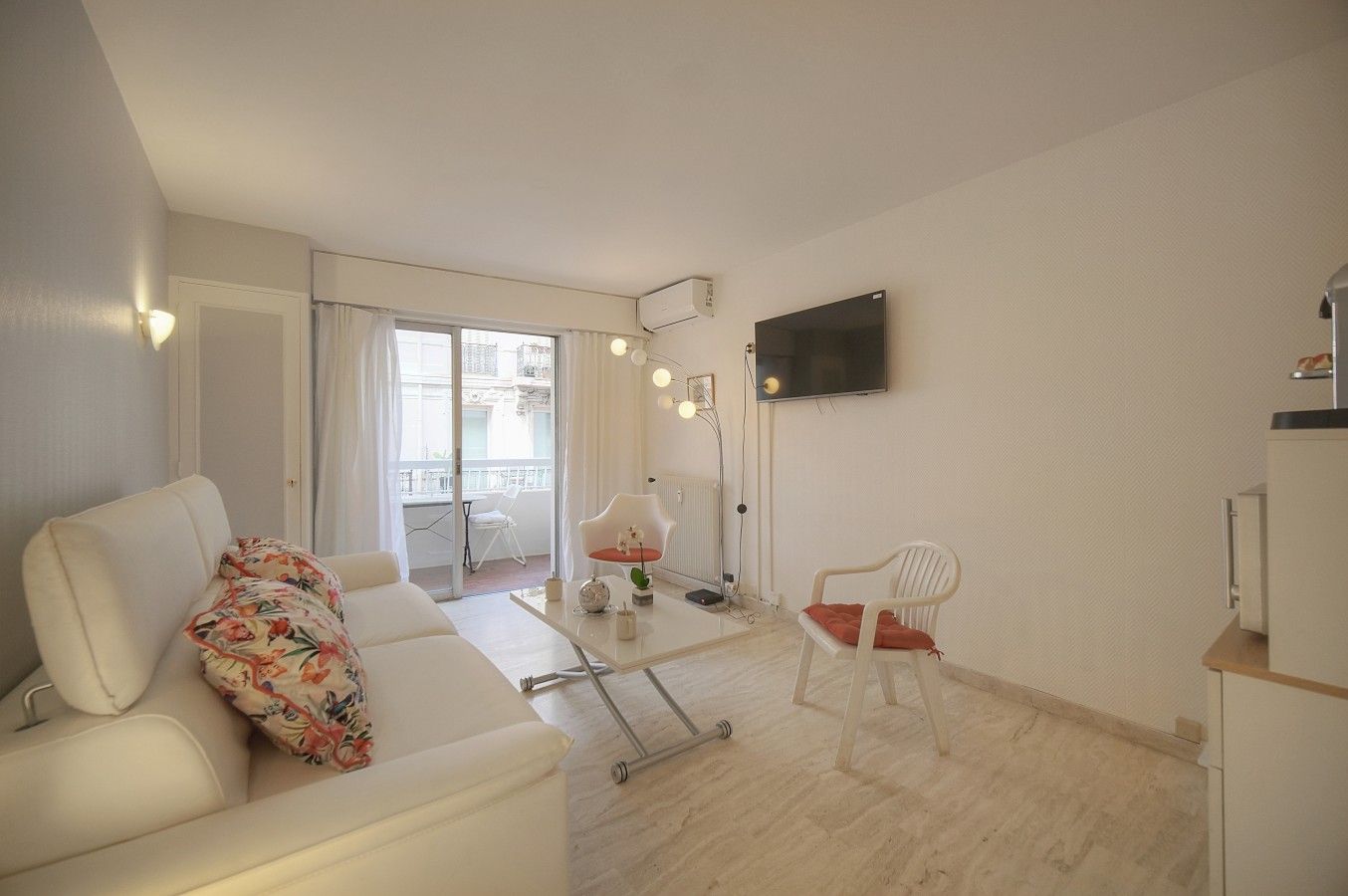 Een moderne woonkamer met een bank, een fauteuil, een salontafel en een aan de muur bevestigde televisie.