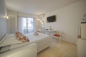 A hotel room with a bed, a desk, a chair, a TV, and a balcony. - One-bedroom apartment in Cannes, France (Cannes)