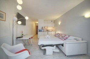 Ein modernes Hotelzimmer mit Bett, Schreibtisch, Stuhl, einer Küchenzeile und einem Badezimmer.