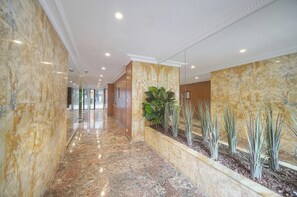 A hotel corridor with marble flooring, a planter with plants, and a mirrored wall. - One-bedroom apartment in France, Cannes (Cannes)