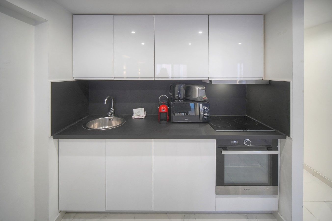 Una cucina compatta con lavello, tostapane, macchina da caffè e forno.